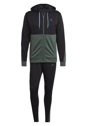 Męska dwukolorowa czarno-ciemnozielona kurtka z kapturem i zamkiem błyskawicznym marki Adidas, z niebieskimi sznurkami i dopasowanymi czarnymi wąskimi spodniami.