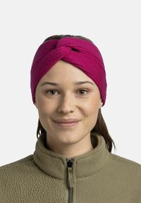 Gestricktes, pinkes Haarband mit einem zwirbelten Design; getragen mit einer beigen Fleecejacke mit Reißverschluss. Glatte Textur und enganliegende Passform.