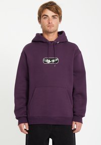 Paarse hoodie van dik materiaal, voorzien van een grote buidelzak aan de voorkant en een grafisch ontwerp met handen in een rechthoek. Met een trekkoord in de capuchon.