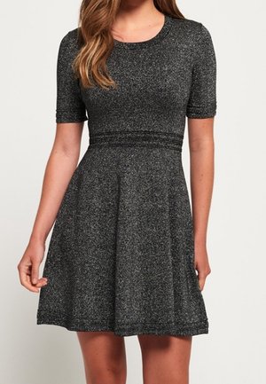 Robe noire à manches courtes avec un corsage ajusté et une jupe évasée, confectionnée dans un tissu texturé avec un effet subtil de scintillement.