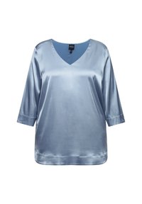 Blusa di seta leggera color azzurro, con scollo a V, maniche a tre quarti e una trama liscia e riflettente, dal taglio morbido.
