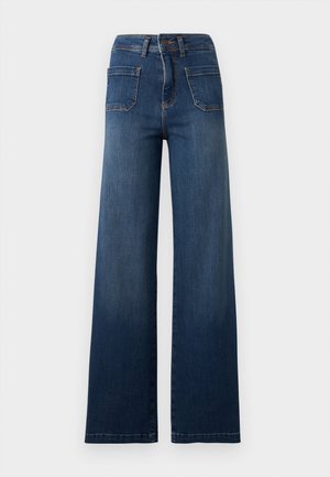 Jean bleu taille haute à jambes larges avec poches plaquées à l'avant, fermeture par bouton et zip, et passants pour ceinture sur un fond uni.