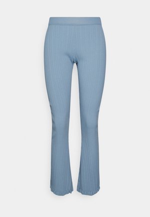 Vaaleansininen ribbed-kudottu toppi lyhyillä hihoilla ja kolmella napilla, yhdistettynä samansävyisiin ribattuihin leveneviin housuihin ja kermaiseen käsilaukkuun.