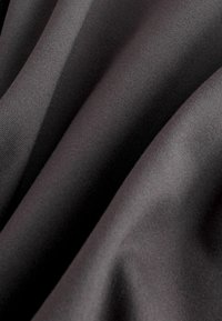 Melnā auduma ar gludu tekstūru, kas izceļas ar mīkstiem krokiem un smalku spīdumu, rādot dažādas nokrāsas kroku dēļ.