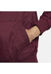 Bordo jakna z gubanjem, z sprednjim žepom in rebrastimi manšetami za prilegajoč zaključek. Očitne šive.