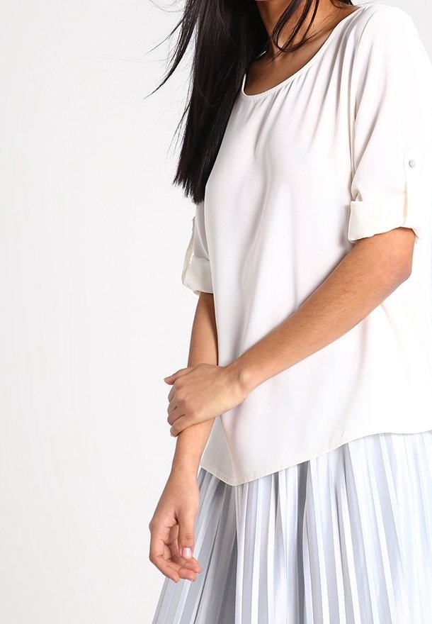 White short-sleeve blouse with a rounded neckline and rolled sleeves, paired with a pleated light blue skirt. Smooth fabric texture.