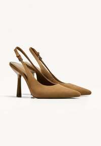 Korkeakorkoiset tanssuede-slingback-kengät, joissa on terävä kärki, säädettävä nilkkahihna ja kapea stiletto-korko. Sileä pinta ja minimalistinen muotoilu.