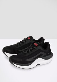 Scarpe sportive nere con tomaia in rete, tallone rinforzato, suola intermedia bianca e accenti rossi sul logo e sugli occhielli. Design con lacci e motivo testurizzato.