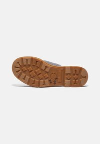 Gray rubber sole with deep treads, featuring a Timberland logo and brand name. Textured surface for grip and durability.