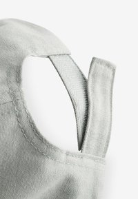 Grå tygrem med en texturerad yta, med ren sömnad och en förlängd loop-design. Bakgrunden är helt vit.