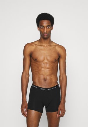 Sorte bomuldsboxer shorts med en hvid "TOMMY HILFIGER" logoelastik, der har en tætsiddende design og glat tekstur.