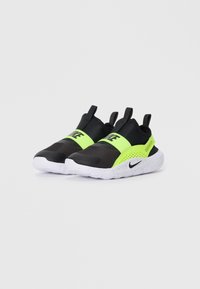 Baskets slip-on noires et vert néon avec un dessus texturé, une semelle mouchetée blanche et un logo noir proéminent sur la bande.