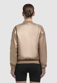 Saténová taupe bomber bunda s rebrovaným golierom a manžetami, s bočnou kapsou a hladkým povrchom. Pohľad zozadu ukazuje priliehavý strih.