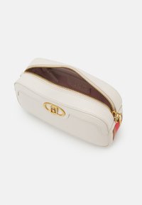 Borsa in pelle crema con una texture liscia, hardware dorato, chiusura con zip e un accento rosso e beige sul lato. Interno foderato in tessuto marrone.