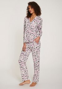 Langärmliges Pyjama-Set aus weichem Stoff mit einem abstrakten Muster in Rosa, Schwarz und Weiß. Das Oberteil hat einen Knopfverschluss vorne und Seitentaschen.
