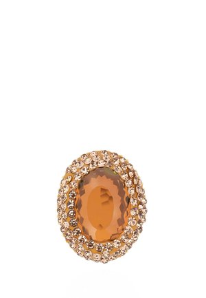 Oval-cut orange gemstone surrounded by two rows of small round light orange crystals in a gold setting.