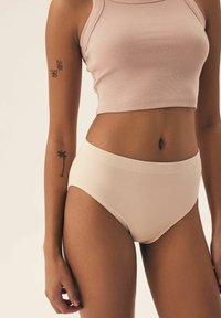 Jasno-beżowe, prążkowane, bawełniane majtki o wysokim stanie w zestawie z pasującym, miękkim różowym prążkowanym crop topem, oba o gładkiej fakturze.