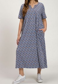 Maxiklänning i blått tyg med blommönster i orange och vitt. Korta ärmar, v-ringning och två sidofickor. Matchad med vita sneakers.
