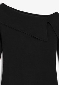 Jersey negro de hombros descubiertos con textura acanalada, que presenta un detalle de borde con forma de ondas a lo largo del escote, diseñado con una silueta ajustada.