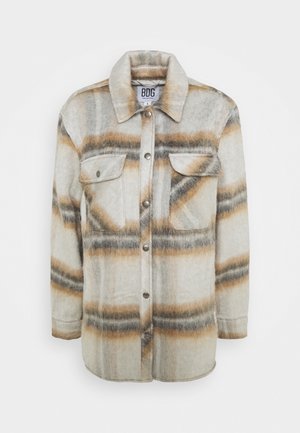 Lehká flanelová košile-jacket v kostkovaném vzoru s krémovými, hnědými a šedými barvami, s knoflíkovým zapínáním, dvěma náprsními kapsami a límečkem.