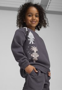 Sudadera gris oscuro con gráficos de trolls de dibujos animados en colores claros, con mangas largas y un corte relajado, combinada con pantalones a juego.