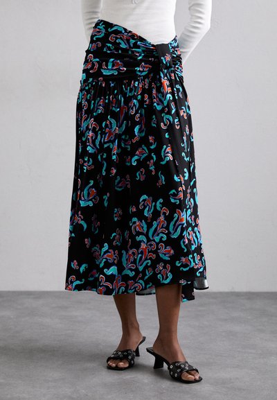 Zwarte midi-rok met teal en rode bloemmotieven, geraffineerde tailleband, gedragen met zwarte haksandalen en een witte shirt met lange mouwen.