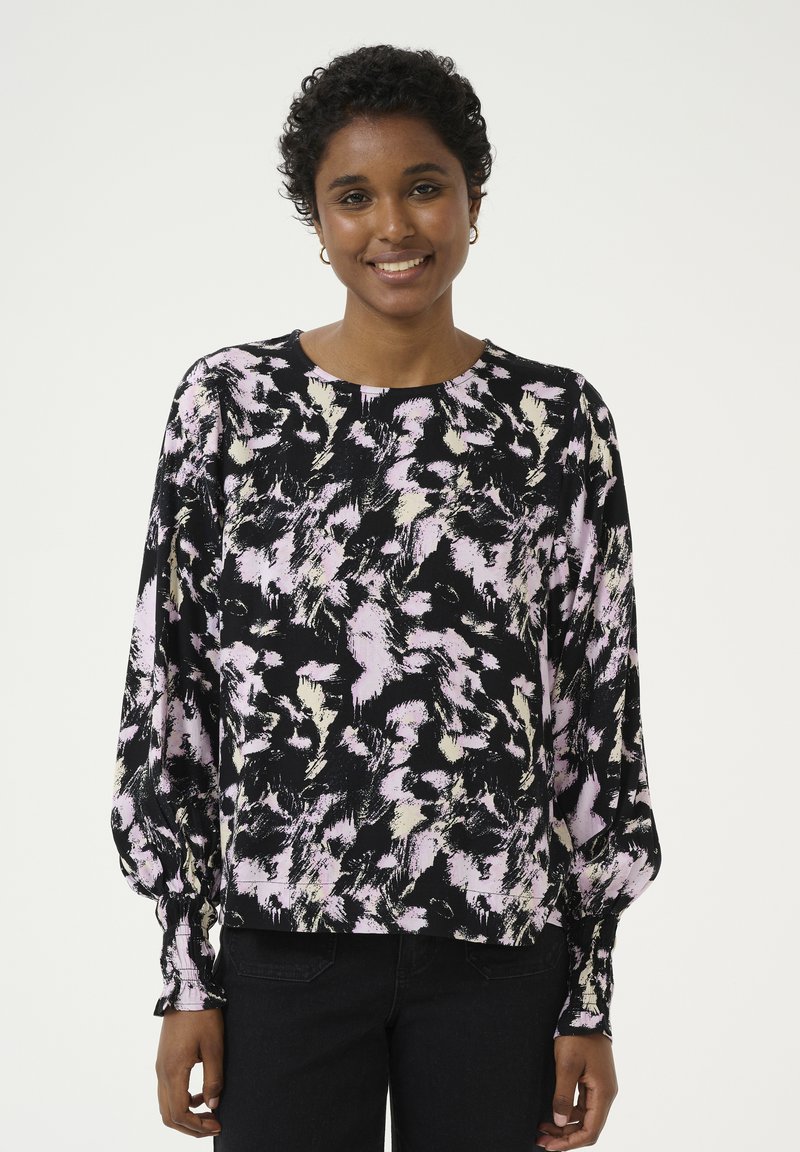 Blusa a maniche lunghe nera con un motivo astratto rosa e crema, scollatura rotonda e polsi aderenti. Tessuto morbido e testurizzato.
