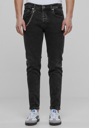 Black denim jeans with a slim fit, featuring silver hardware, a chain hanging from the belt loop, and subtle fading in the fabric.