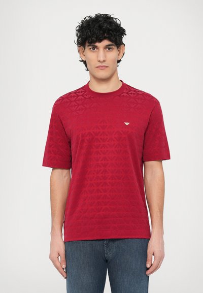 Red patterned t-shirt featuring a textured geometric design, crew neckline, and short sleeves. Small logo accent on the chest.