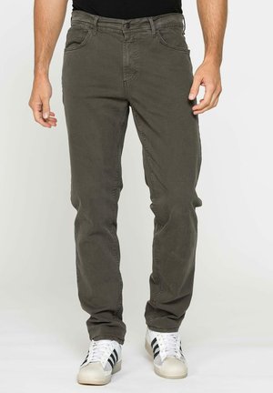 Pantaloni casual verde oliva in cotone. Hanno un design a gamba dritta, tasche frontali e chiusura con bottone. Abbinati a sneaker bianche.