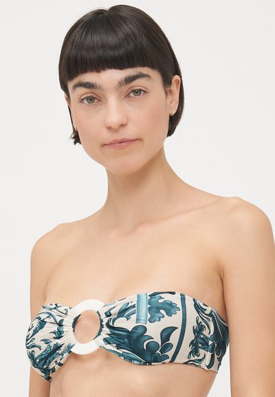Bandeau bikini in white with teal floral pattern, featuring a central ring detail and gathered fabric for texture. Smooth finish.