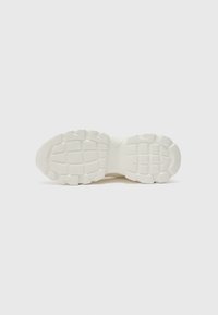 Hvit sneakersåle med teksturert gummigrep, med en bred, flat form og distinkt mønster for trase.