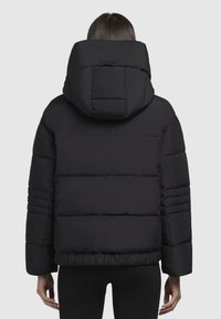 Zwarte pufferjack met capuchon, voorzien van een gewatteerde textuur en horizontale naden, ontworpen voor warmte en comfort.