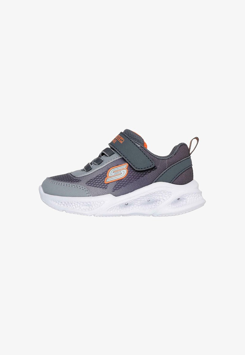 Zapatilla deportiva gris con parte superior de malla, suela de goma y suela blanca. Correa de Velcro y acentos naranjas en la lengüeta y el logotipo.