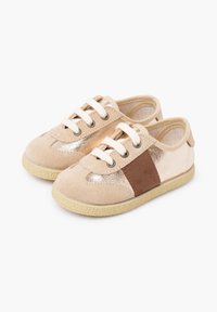 Béžové tenisky kombinující semiš a kovové prvky, hnědé boční panely a texturované gumové podrážky, se šňůrkami v bílé barvě.