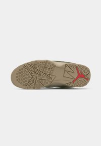 Suela de zapatilla verde oliva con patrón de banda de rodadura geométrico y logo Jumpman rojo en la suela de goma beige.