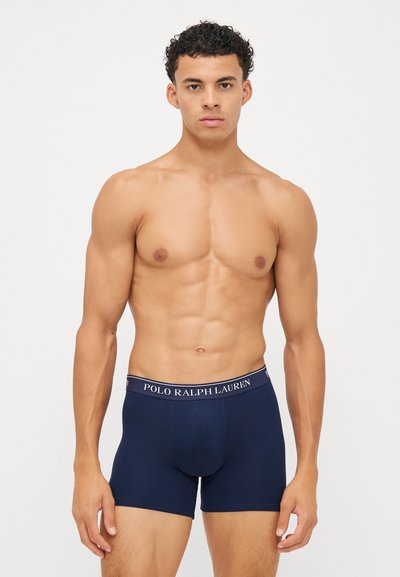 Tumši zili bokseršorti ar pieguļošu dizainu, elastīgu jostu, uz kuras redzams "POLO RALPH LAUREN" logo, izgatavoti no mīkstas, elastīgas audiem.