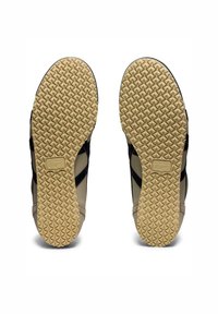 Buty sportowe z czarną, fakturowaną cholewką i kremową gumową podeszwą z wzorem w diamenty. Wytłoczone logo marki na podeszwie.