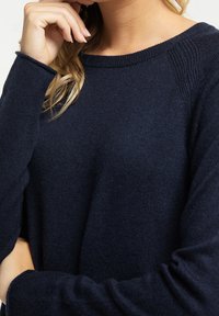 Dunkelblauer Pullover aus weichem Strickstoff, mit weit geschnittenem Ausschnitt, langen Raglanärmeln und Rippdetails an den Bündchen und dem Saum.