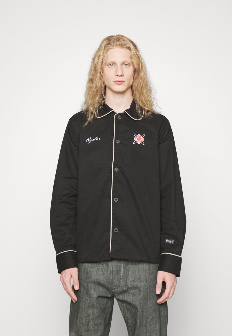 Fekete gombos ing kontrasztos világos szegéllyel, bal mellrészen hímzett mintával és laza szabással.