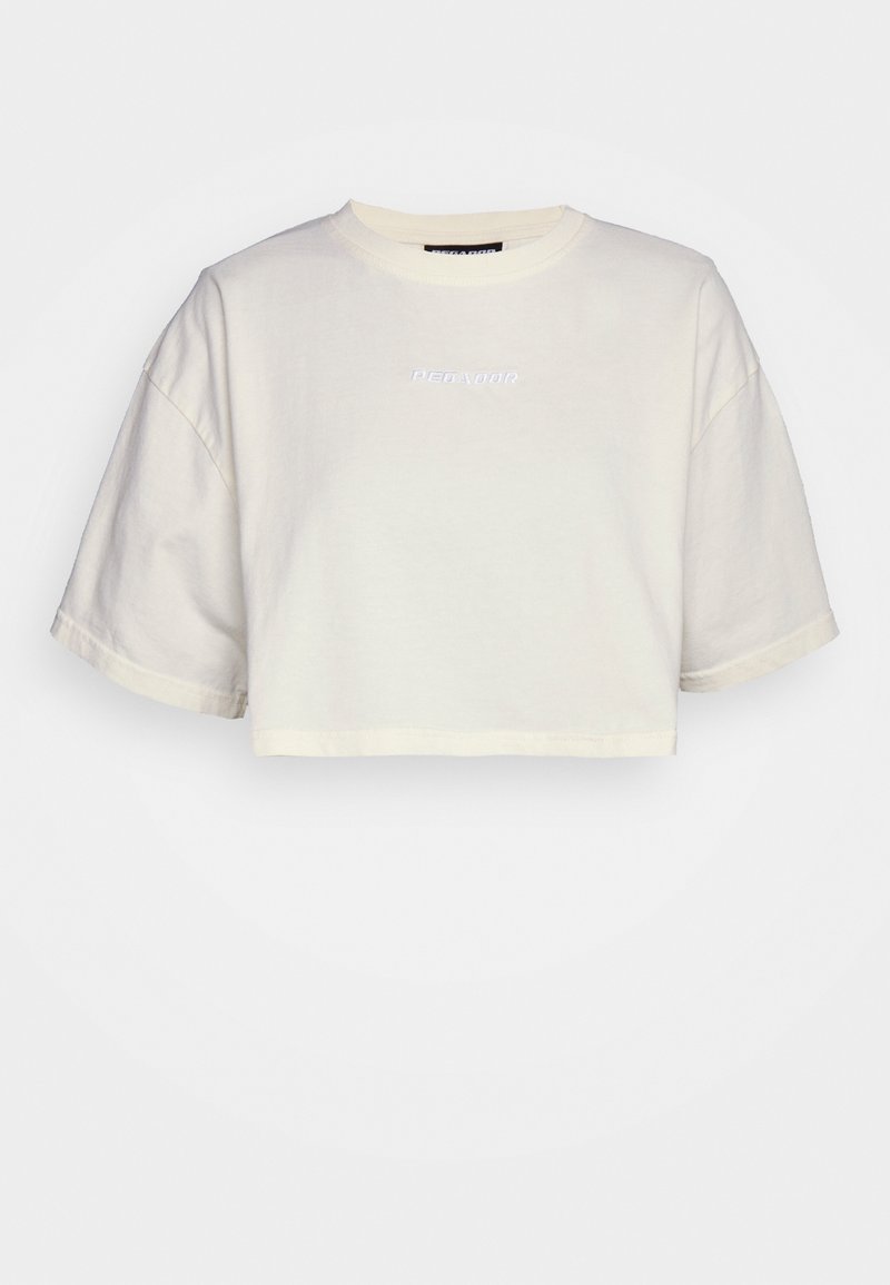 T-shirt court cropped en coton crème avec un col rond et "PEGAZOR" brodé en couleur claire sur le devant.