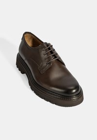 Chaussure en cuir marron à lacets avec un bout arrondi, semelle texturée, couture contrastante et finition lisse. Design à la fois décontracté et structuré.