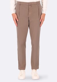 Pantaloni beige a gamba dritta, con pieghe frontali, tasche laterali e passanti per cintura, abbinati a sneakers bianche. Tessuto dalla superficie liscia.