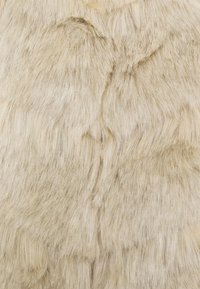 Tissu en fausse fourrure dans des tons beige avec des longueurs de fibres douces variées, arborant une texture subtile et un éclat naturel.