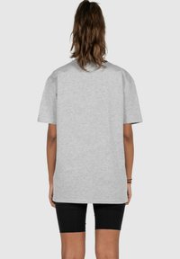 Grau oversized T-Shirt mit kurzen Ärmeln, aus einem Baumwollmischgewebe gefertigt. Verfügt über einen runden Ausschnitt und ein einfaches, klares Design.