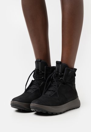 Black suede ankle boots with a textured finish, featuring a padded collar, lace-up design, and a sturdy rubber sole for grip.