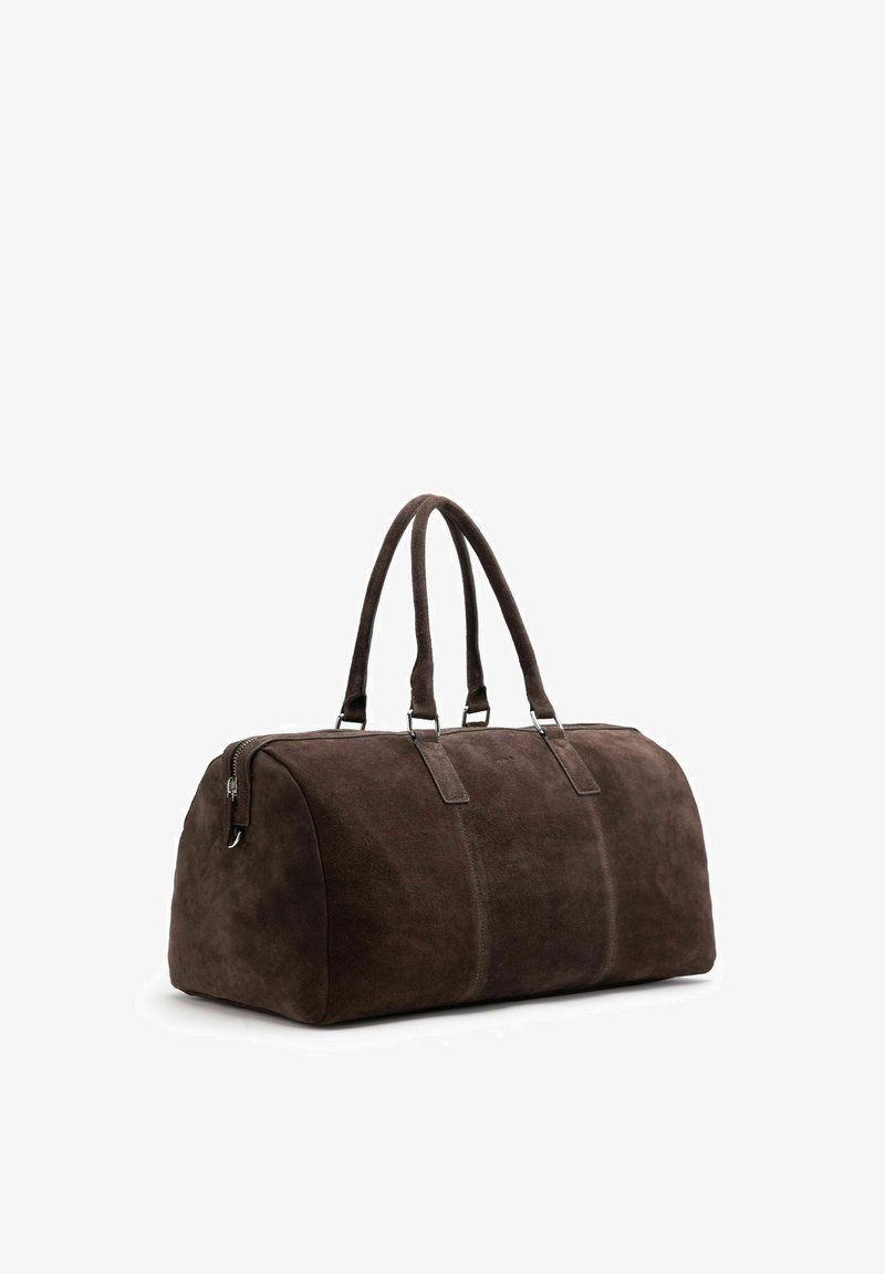 Dark brown suede duffel bag with double handles and zipper closure, shown standing on a white background.
