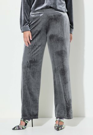 Pantalones de terciopelo gris de pierna ancha con una textura suave y cinturilla elástica, combinados con zapatos de tacón alto de tiras multicolores.