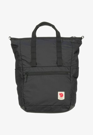 Sac en nylon noir avec poignées supérieures doubles, poche avant zippée et patch logo. Possède une texture douce et une forme rectangulaire.