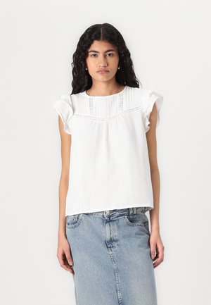 Haut en coton blanc avec des manches courtes à volants, des détails plissés et des accents en dentelle au niveau du col, associé à une jupe en denim bleu clair.